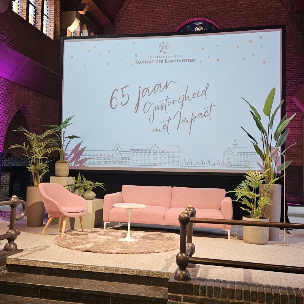 Podium in een conferentiehotel aangekleed met kunstplanten in grote potten