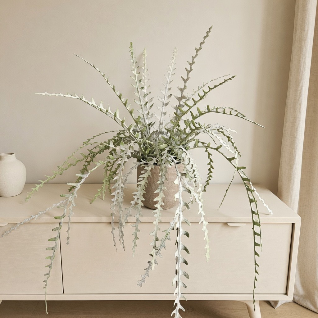 Kunstplant met zilvergroen hangend blad in een stenen pot op een licht dressoir